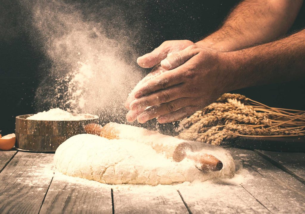 Man rolling dough into bread