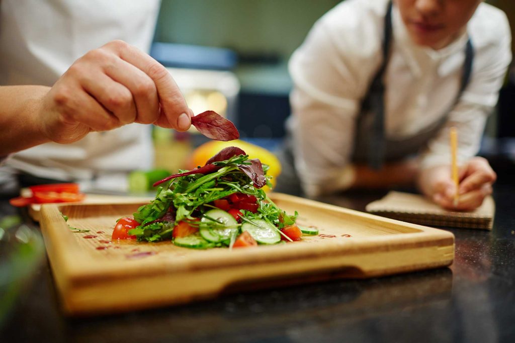 Chefs in a kitchen garnishing plate